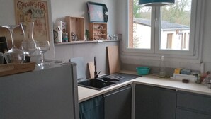 Une cuisine avec un carrelage à motifs, une fenêtre et un luminaire suspendu.
