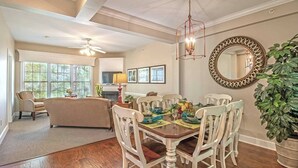 A dining area with a wooden table, white chairs, and a chandelier. - Sleeps 12 - Large 4BR Townhome, Indoor/Outdoor Pool, Golf, Close To Theme Parks! (Williamsburg)