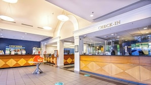 A hotel reception area with a 'Check-In' desk, a concierge desk, and a tiled floor with directional markers. - Spacious 3BR Cottage - Family Friendly Resort - Close to Theme Parks (Williamsburg)
