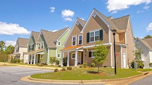 A row of townhouses with pitched roofs, front porches, and a well-maintained lawn. - Spacious 3BR Cottage - Family Friendly Resort - Close to Theme Parks (Williamsburg)
