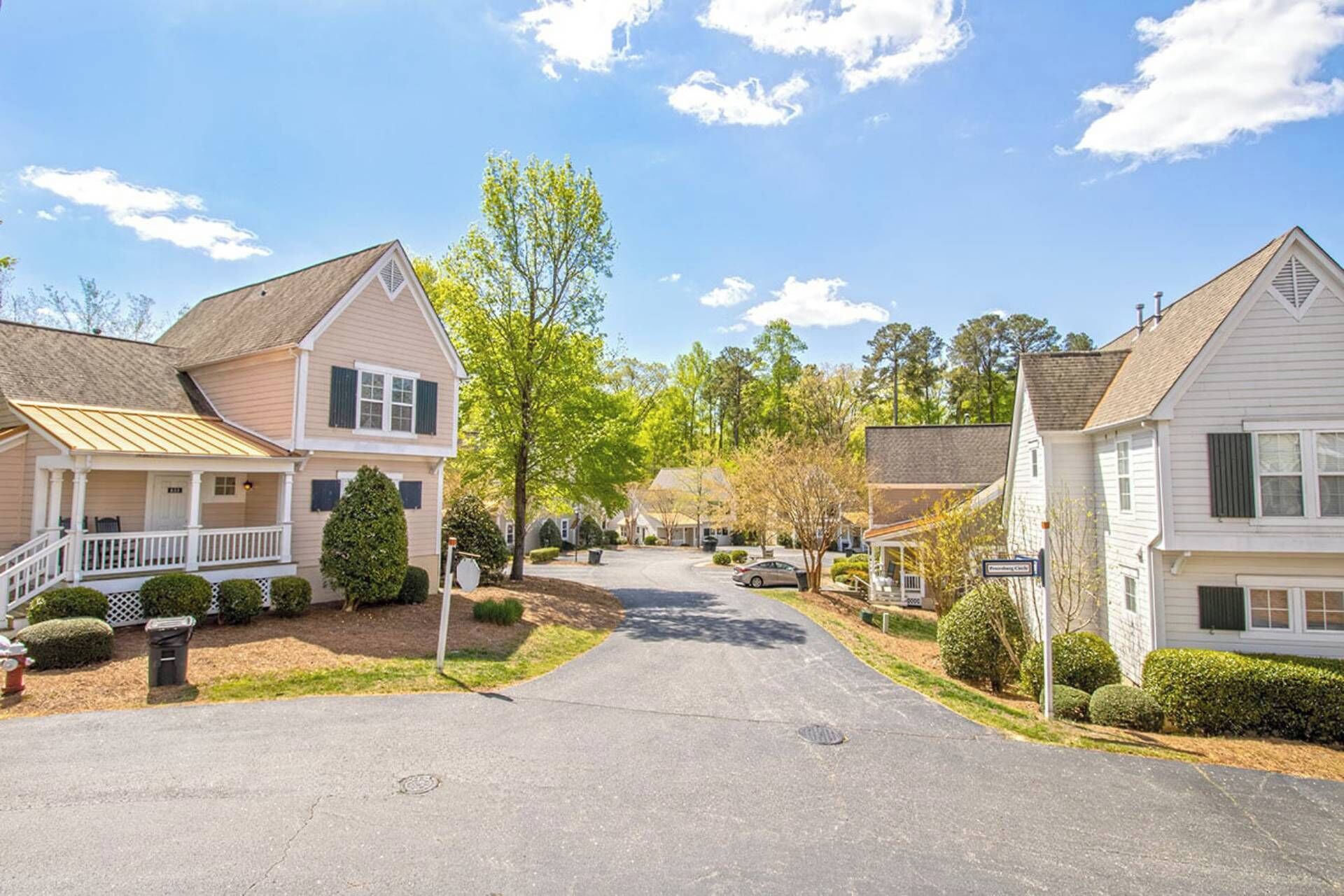 A quiet residential street with single-family homes, a clear sky, and a well-maintained lawn.