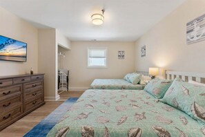 A bedroom with two beds, a dresser, a window, and a painting on the wall.