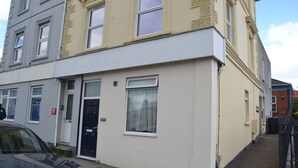 A two-story residential building with a white facade and a black door.