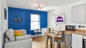 A compact living space with a dining area, kitchenette, and a blue accent wall.