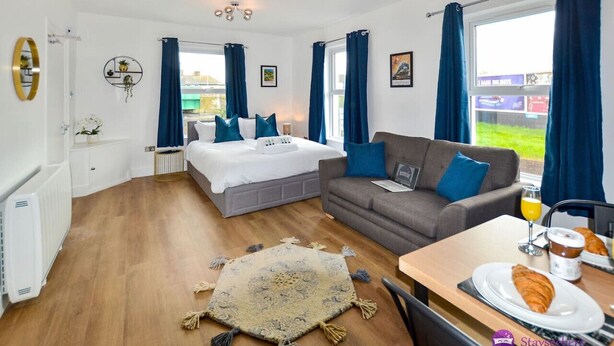 A hotel room with a bed, a sofa, a dining table with breakfast, and a view of the outside.