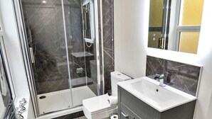 A modern bathroom with a glass-enclosed shower, a white toilet, and a vanity with a mirror.
