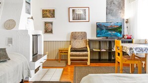 Une pièce confortable avec un lit, une chaise, un bureau et un téléviseur. Les murs sont ornés de tableaux et il y a une fenêtre avec des rideaux.