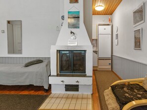 A compact room with a bed, a small seating area, a kitchenette, and a fireplace.