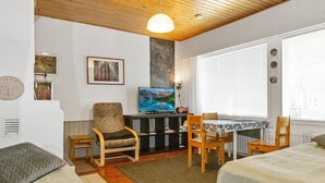 Une pièce confortable avec un plafond en bois, une télévision, un bureau avec une lampe et deux lits.