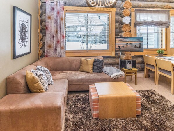 A cozy living room with a brown leather sofa, a wooden coffee table, and a television.
