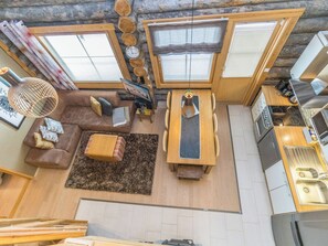 En kompakt opholdsstue med sofa, spisebord, tekøkken og store vinduer.