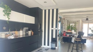 A modern kitchen with black cabinets, a striped wall, and a hexagonal tile floor. - Villa Nyvioni, 3 ch, spa et Piscine (Agde)