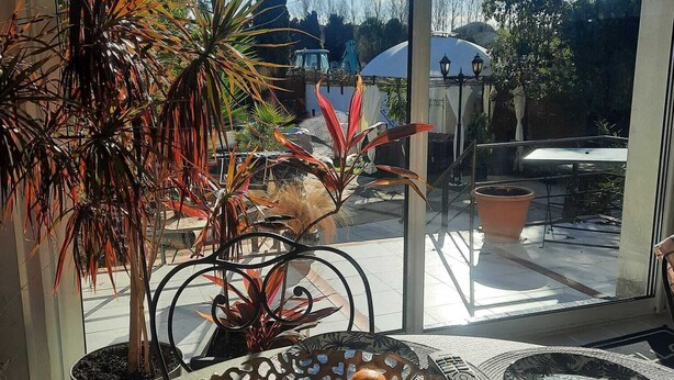 A room with a large window, a potted plant, a table with a basket of oranges, and a view of the outside. - Villa Nyvioni, 3 ch, spa et Piscine (Agde)
