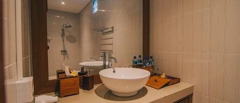 Un baño moderno con un lavamanos grande, un espejo y una zona de ducha.