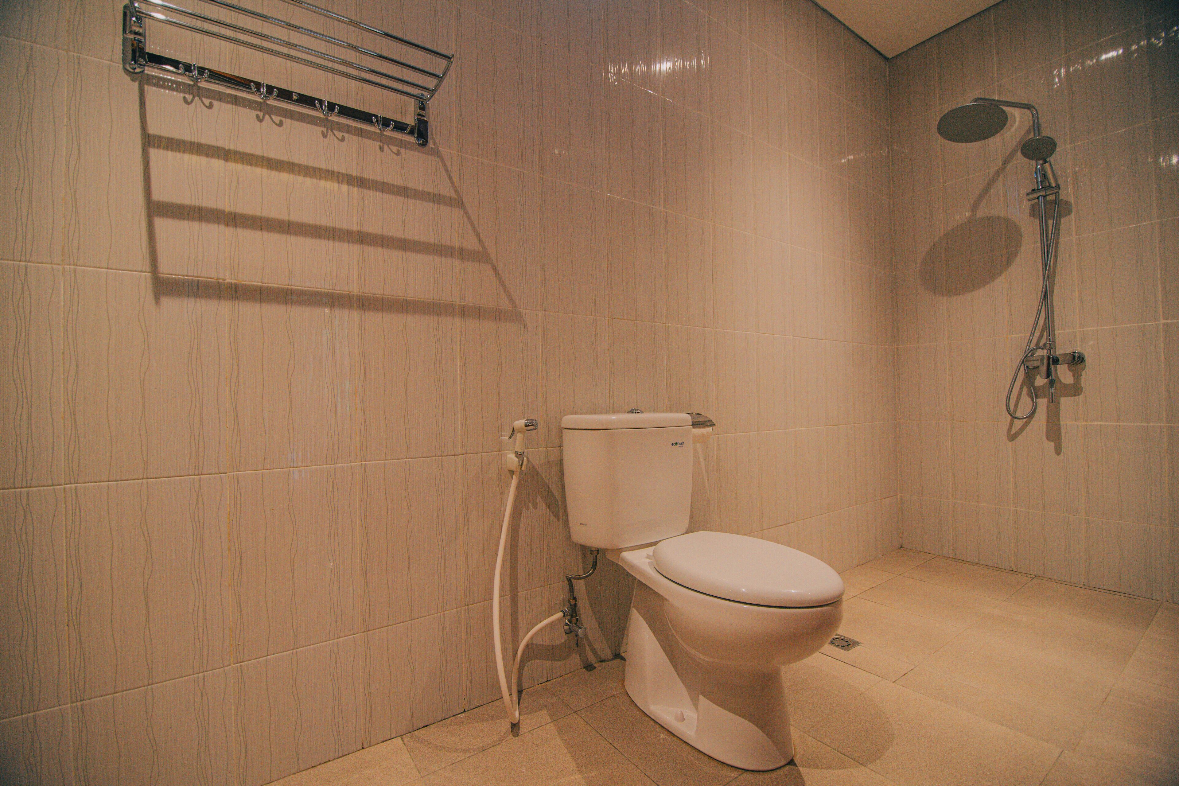 Un baño con inodoro, ducha y toallero.