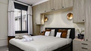 Ein modernes Schlafzimmer mit einem großen Bett, eingebauten Holzschränken und einem Fenster mit Vorhängen.
