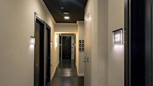 A hotel hallway with a dark floor, light walls, and a ceiling with recessed lighting. - Triple a - Chrisospiliotissis 7 (Athens)