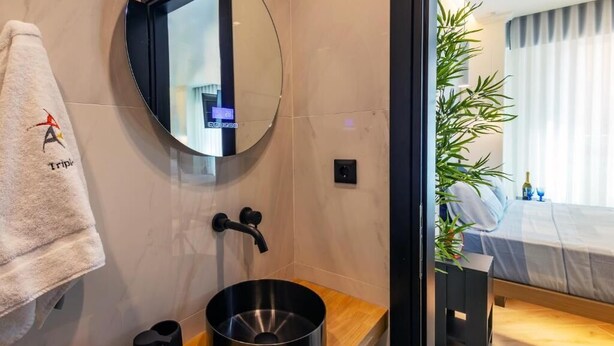 A modern bathroom with a round mirror, a sink, and a towel rack. - Triple a - Chrisospiliotissis 7 (Athens)