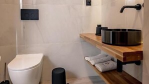 A modern bathroom with a toilet, a sink, and a shower area. - Triple a - Chrisospiliotissis 7 (Athens)