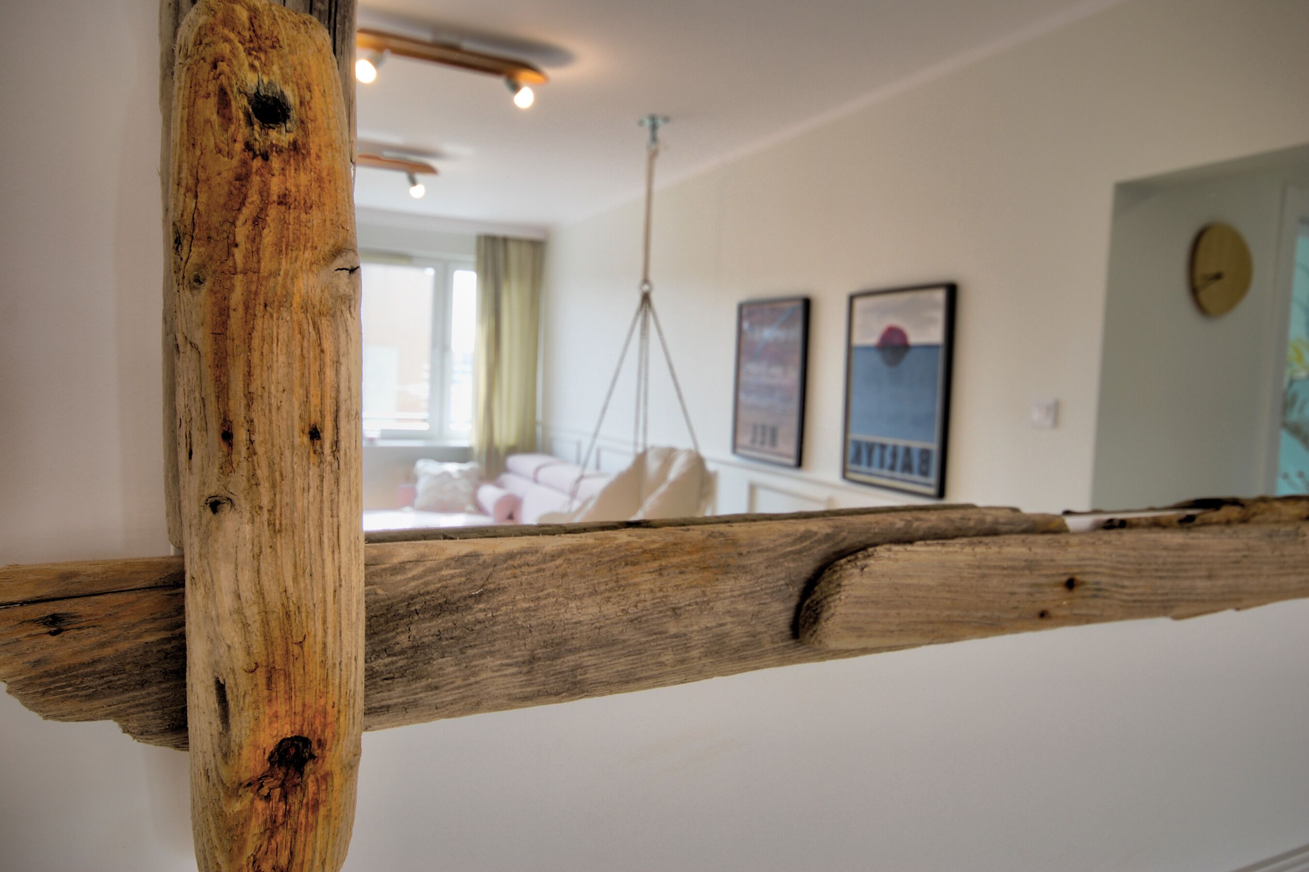 Ein Raum mit Holzbalken, einem Bett, einer Hängeleuchte und gerahmten Bildern an der Wand.