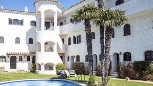 Un edificio blanco grande con varios balcones y una piscina al frente.