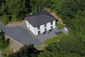 A two-story building with a flat roof, surrounded by dense greenery.
