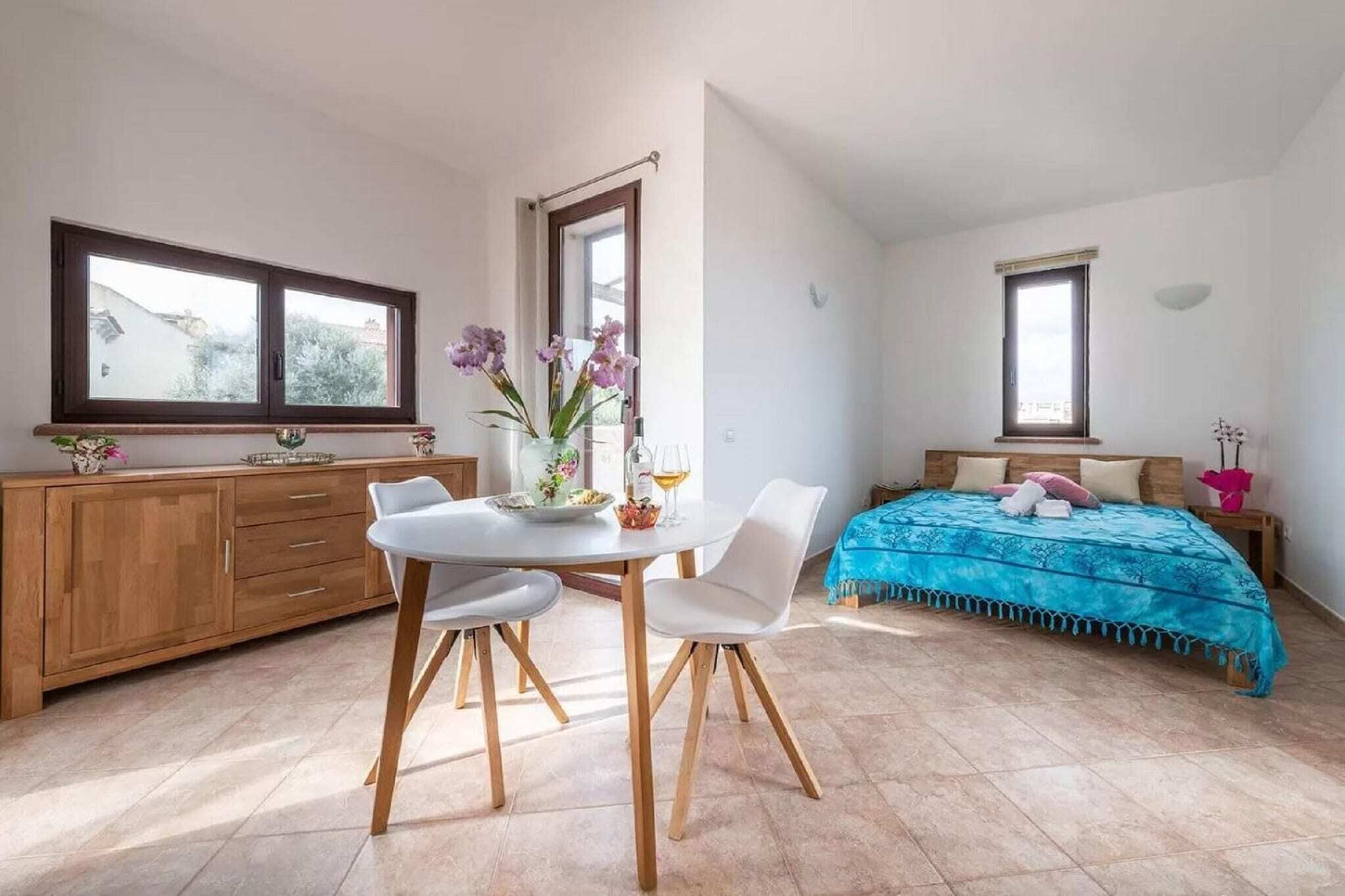 A bedroom with a bed, a bedside table, a window, and a view of the outside.
