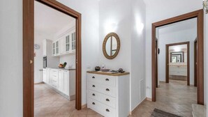 Un pasillo con una zona de cocina, un espejo y un mueble pequeño con cajones.