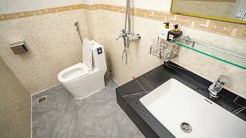 A bathroom with a toilet, a shower, and a sink.