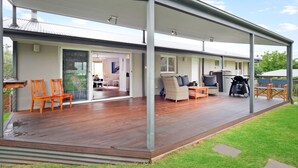 A covered outdoor area with wooden flooring, seating arrangements, and a view into the house. - House Allinga, great for large or multiple families. (Jindabyne)