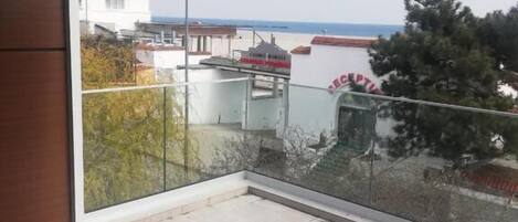 A balcony with a view of the sea and buildings.