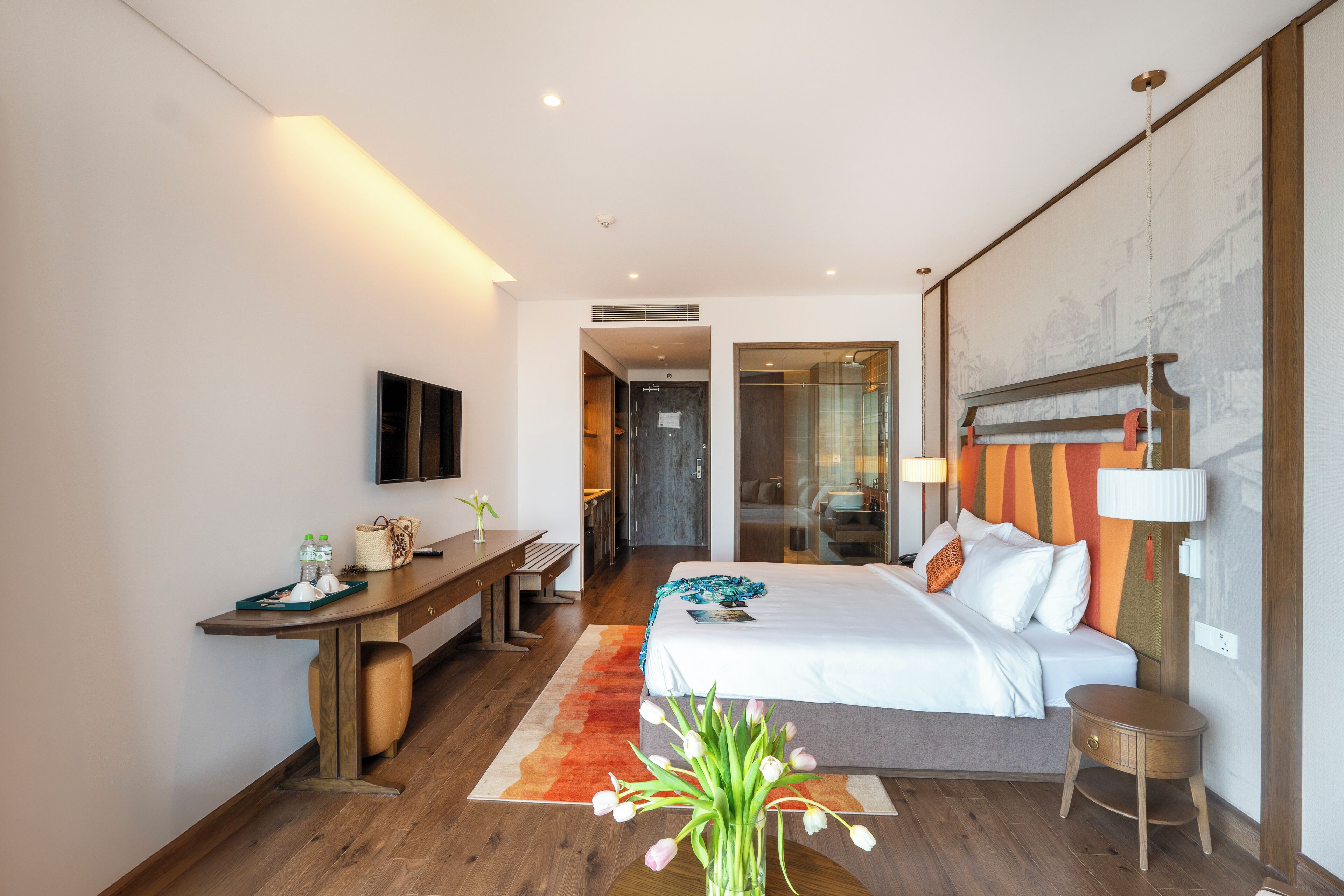 A modern hotel room with a bed, desk, and a large window.