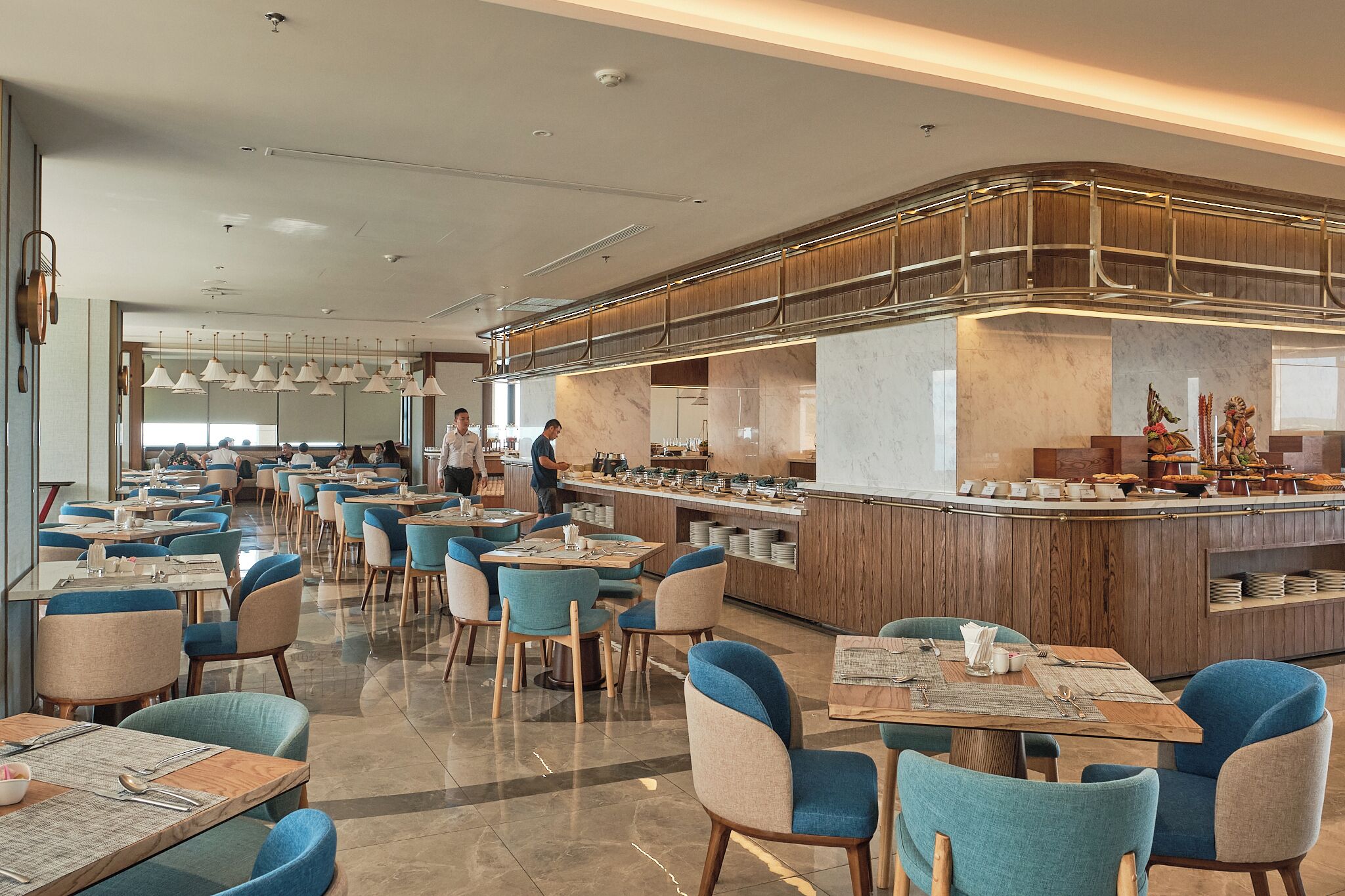 A modern restaurant with a central bar area, multiple dining tables, and chairs.