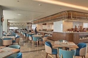 Un restaurante moderno con una barra central, varias mesas para comer y sillas.