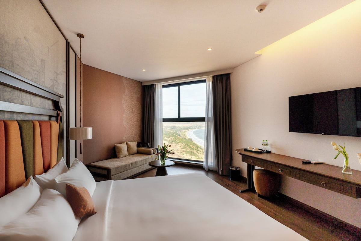 Una habitación de hotel con una cama grande, un sofá, un escritorio y un televisor.