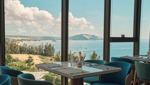 Ein Essbereich mit Blick auf das Meer und ein fernes Gebirge.