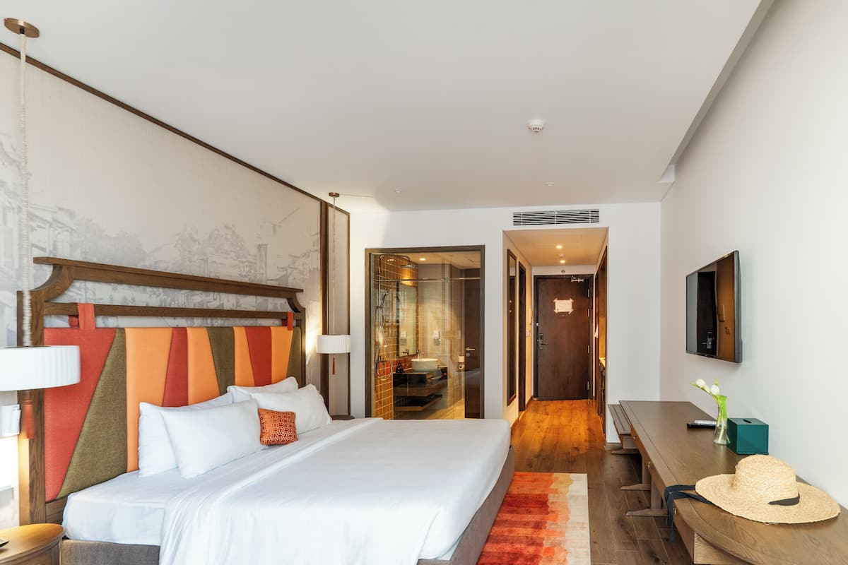 Una habitación de hotel con una cama grande, un cabecero de madera, un escritorio y un televisor.