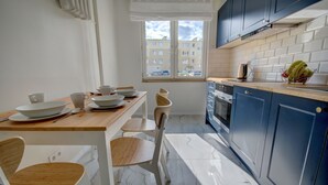Una cocina moderna con una mesa y sillas de madera, una ventana con vistas a edificios y armarios azules.