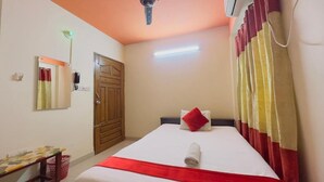 A hotel room with a bed, a desk, a mirror, a door, and a ceiling fan. - Hotel The Sylhet Int. (Dhaka)