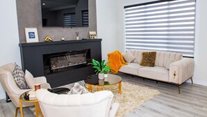 A modern living room with a fireplace, a sofa, a coffee table, and a TV mounted on the wall.