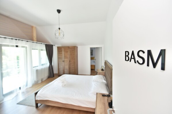A modern bedroom with a large bed, wooden floor, and a large window. - Mira by Atra (Valea Doftanei)