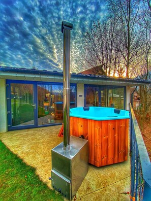 A modern house with a hot tub, a chimney, and a glass door leading to a deck. - Mira by Atra (Valea Doftanei)