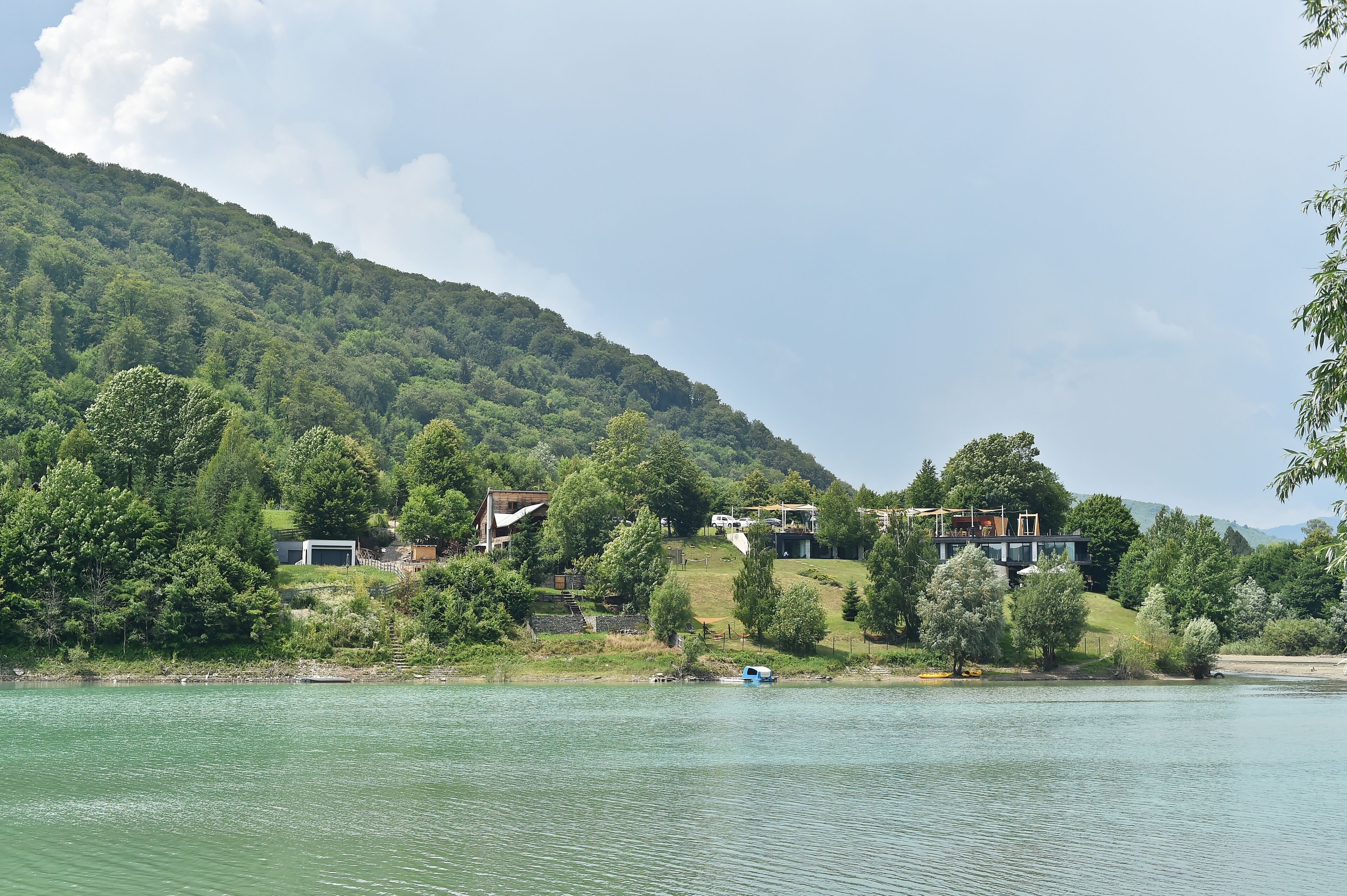 A lakeside property with a house on a hillside, a dock, and a boat.