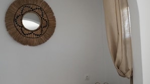 A minimalist room with a wooden bench, a woven wall decoration, and a large mirror. - Yi & Thalassa by KHI Collection (Kithnos)