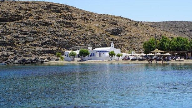 A coastal building with a white facade, a small tower, and a beach area with umbrellas. - Yi & Thalassa by KHI Collection (Kithnos)