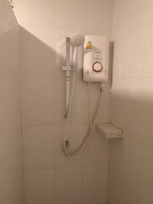 A shower enclosure with a control panel, a handheld showerhead, and a wall-mounted faucet.
