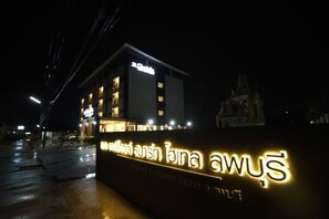 A building with illuminated signage, including a prominent sign with Thai script. - The Charlotte Smart Hotel Lopburi (Lop Buri)