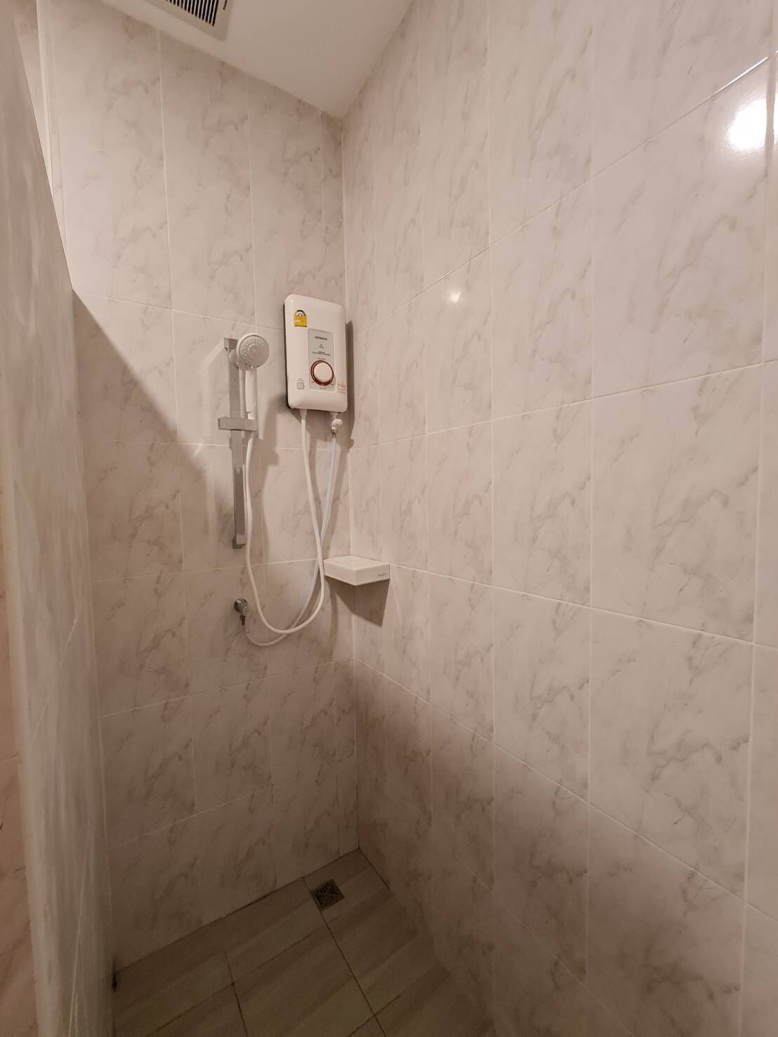 Un área de ducha con cabezal de ducha manual y panel de control en la pared.