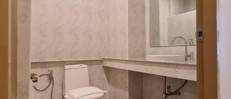 Une salle de bain avec des toilettes, un lavabo et un miroir.