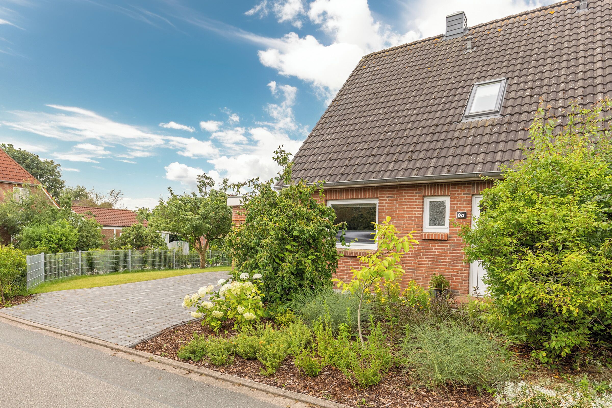 A residential house with a paved driveway, a brick exterior, and a small window.